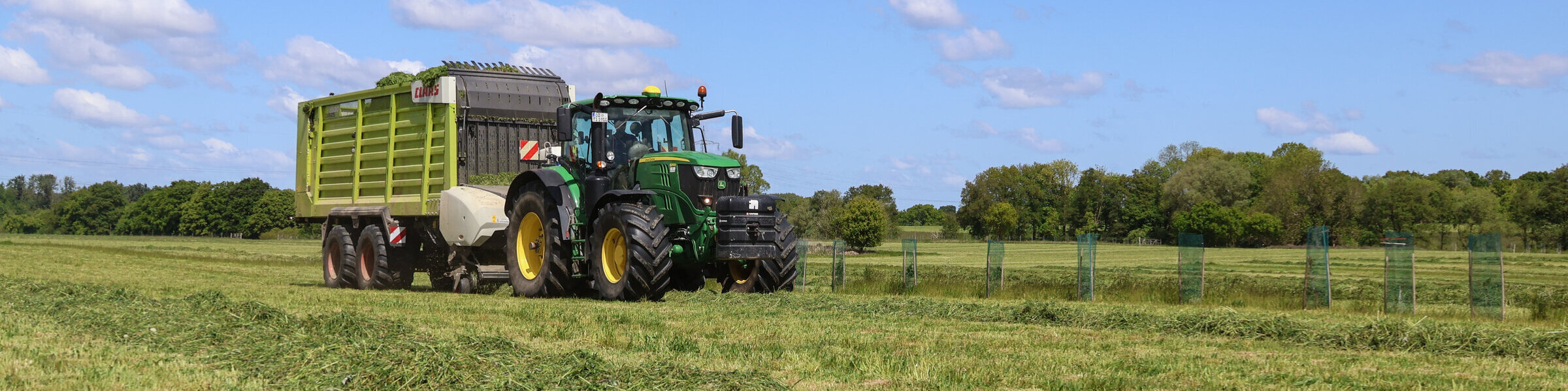 Grünlandnutzung auf dem Versuchsfeld in Trenthorst. Ein Trecker sammelt den Grünlandschitt auf dem Feld ein.