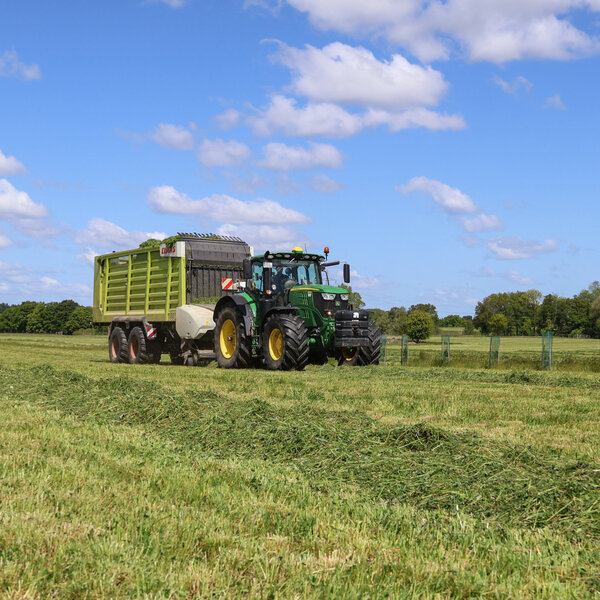 Grünlandnutzung auf dem Versuchsfeld in Trenthorst. Ein Trecker sammelt den Grünlandschitt auf dem Feld ein.